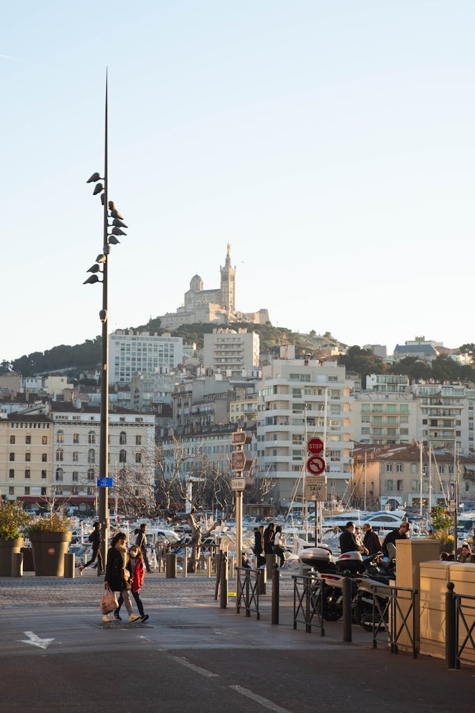 People strolling by the Vieux-Port with a view of Notre-Dame de la Garde in Marseille, France.
